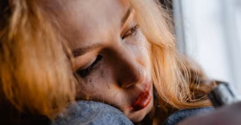 Close-up of a woman with red hair in a thoughtful and emotional moment indoors.