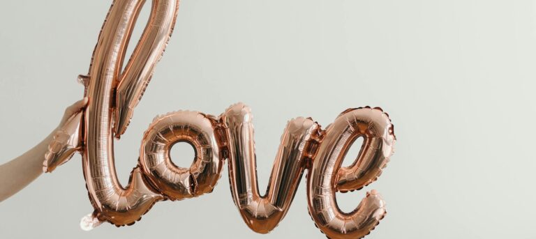 Elegant rose gold balloon spelling 'love' on a soft background, perfect for Valentine's Day themes.