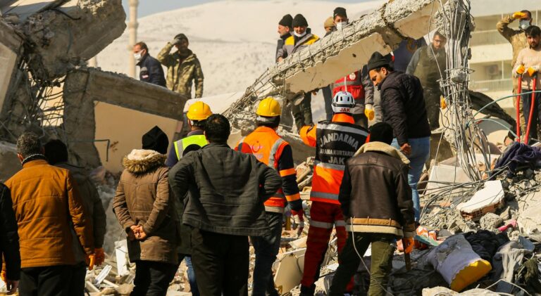 Rescue workers and civilians gathered on rubble after a devastating earthquake in Kahramanmaraş, Türkiye.