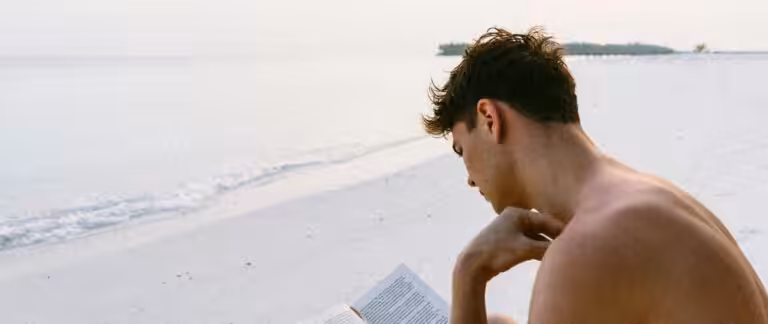 A man enjoys reading a book on a serene Maldives beach, capturing the essence of relaxation.